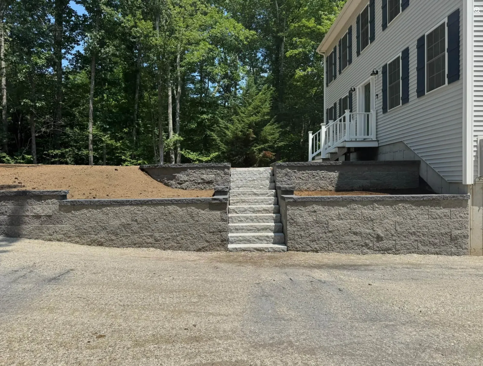 Finished retaining walls and stone steps beside a New Hampshire home